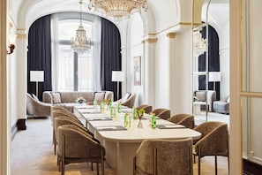 A formal dining room with a long table, multiple chairs, and a chandelier.