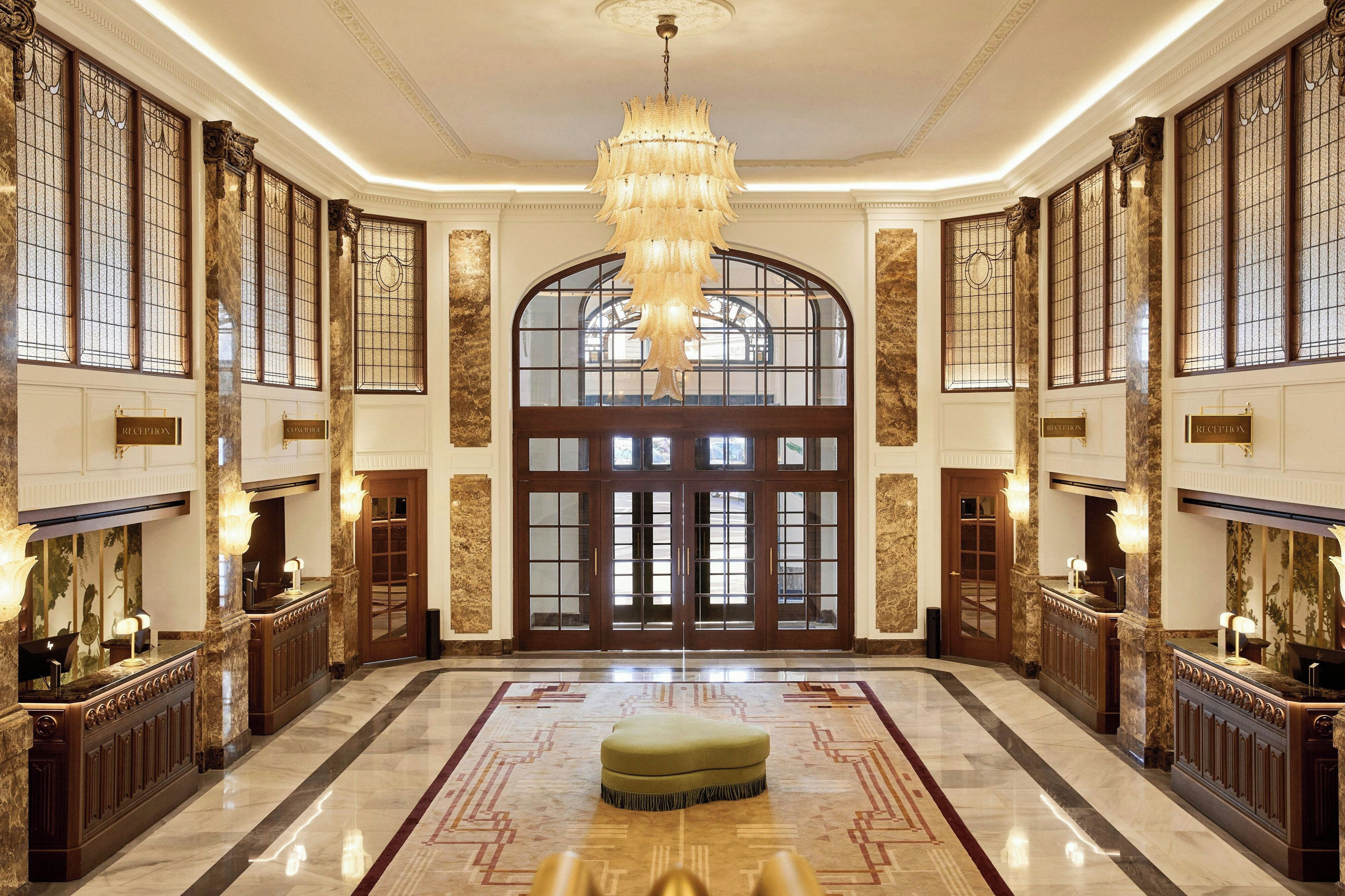 A grand lobby with a large chandelier, a reception desk, and a reception area.