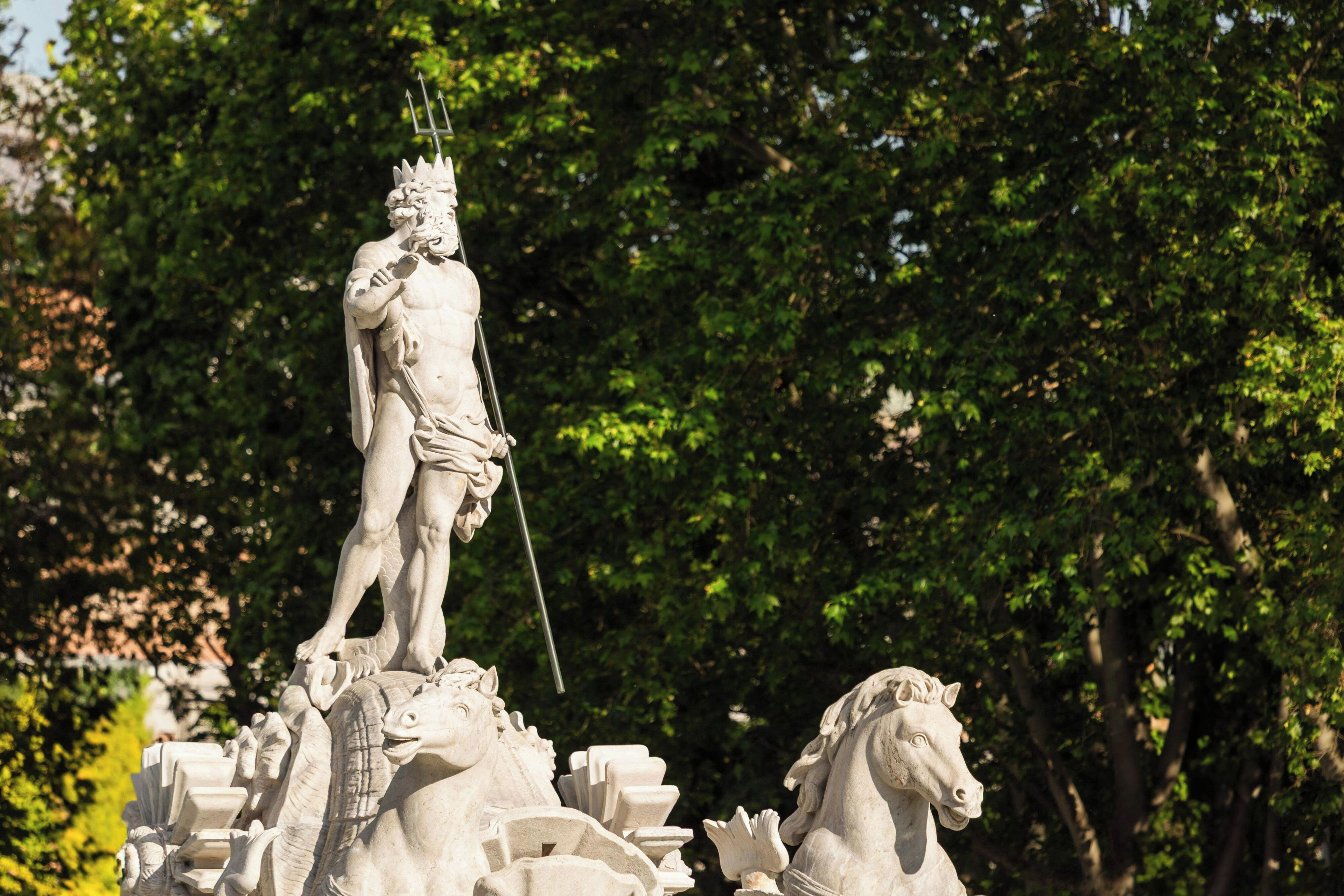 A classical statue of a figure holding a spear, standing on a pedestal with a horse.