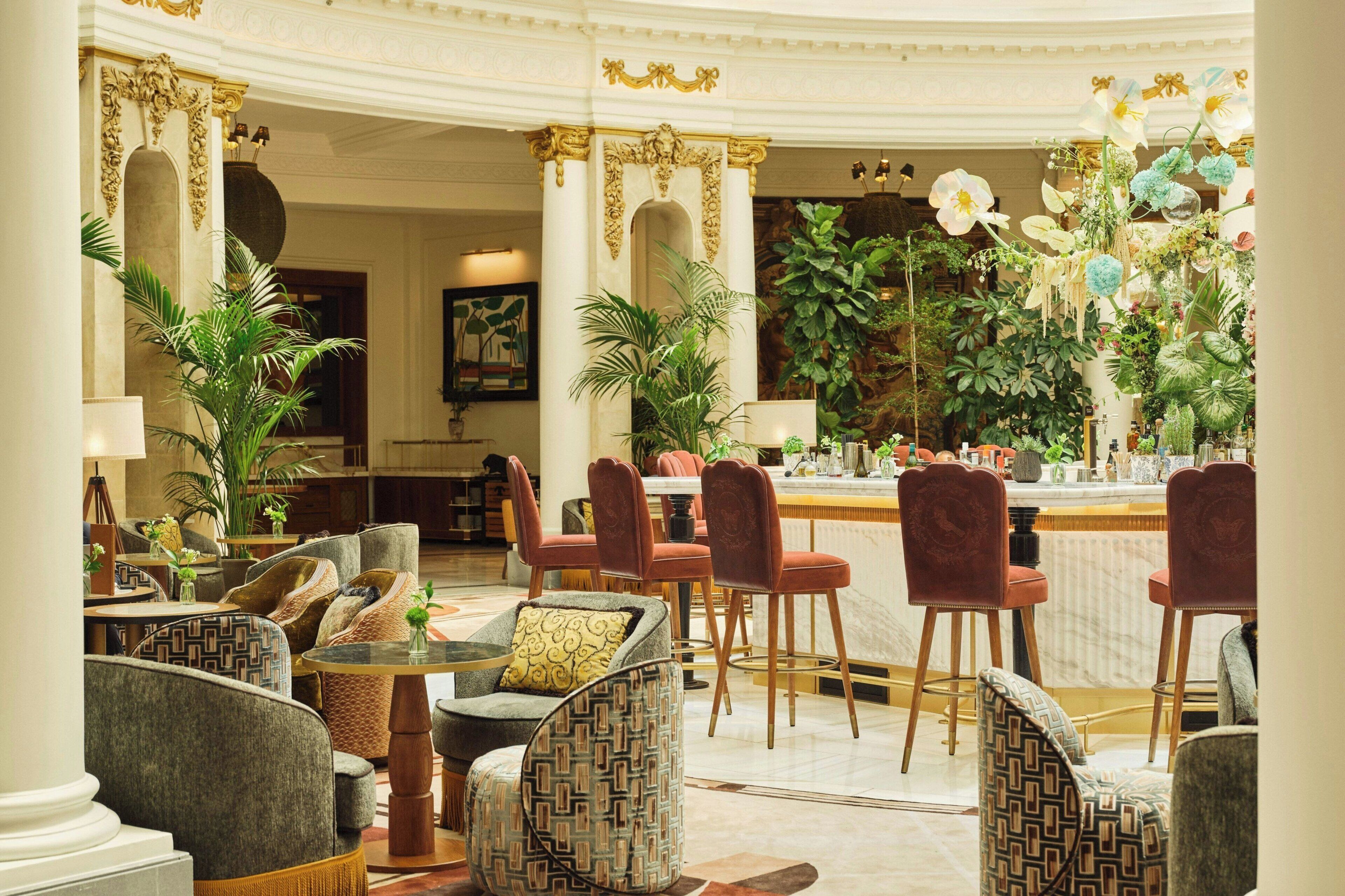 Un vestíbulo con zona de bar, asientos y plantas decorativas.