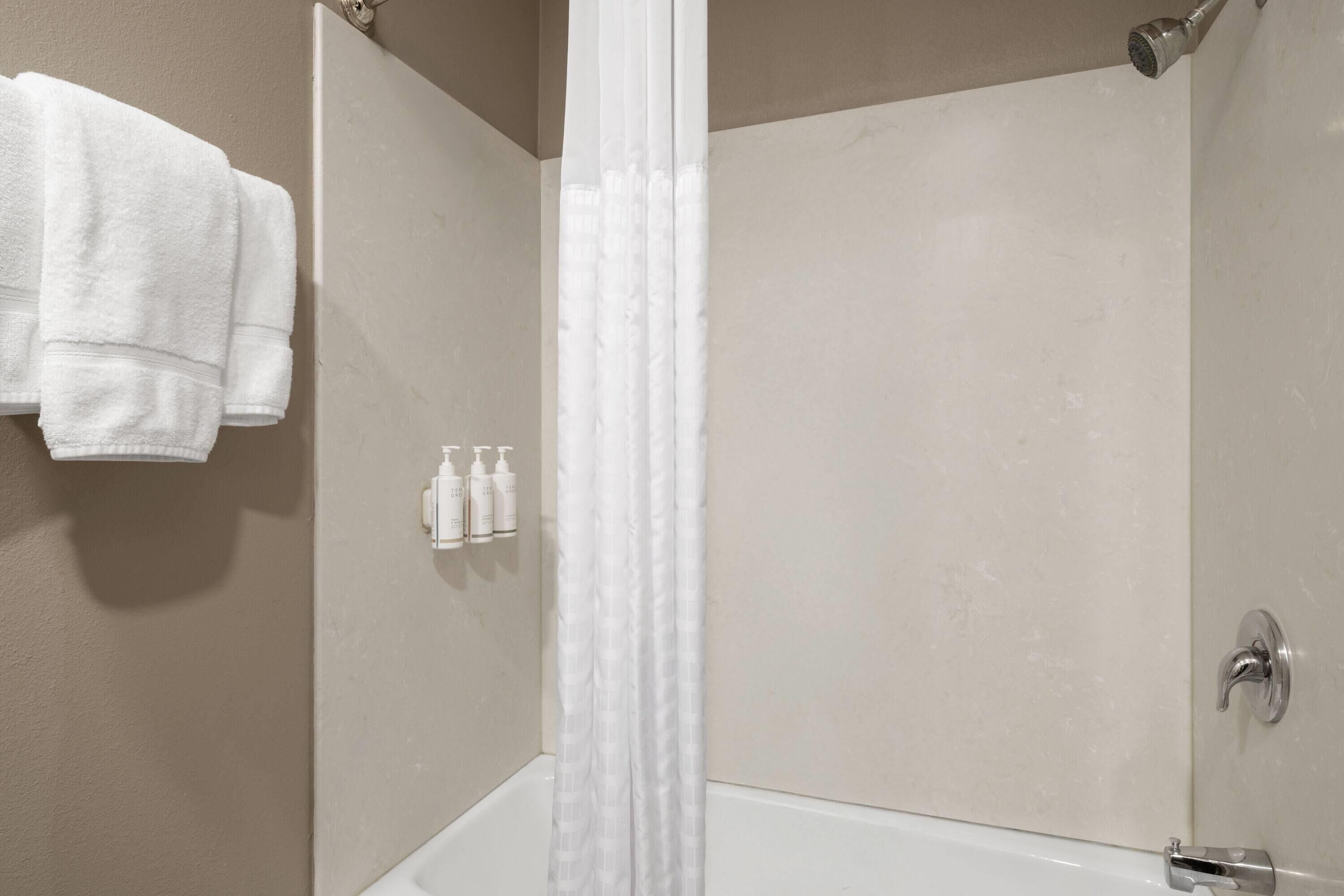 A bathroom with a bathtub, a shower curtain, and a towel rack with towels.