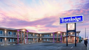Un motel Travelodge avec un bâtiment à deux étages, de nombreux balcons et un panneau indiquant les réductions pour les personnes âgées, le Wi-Fi et la télévision par câble.