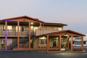 A two-story building with a covered entrance, a staircase, and a balcony.