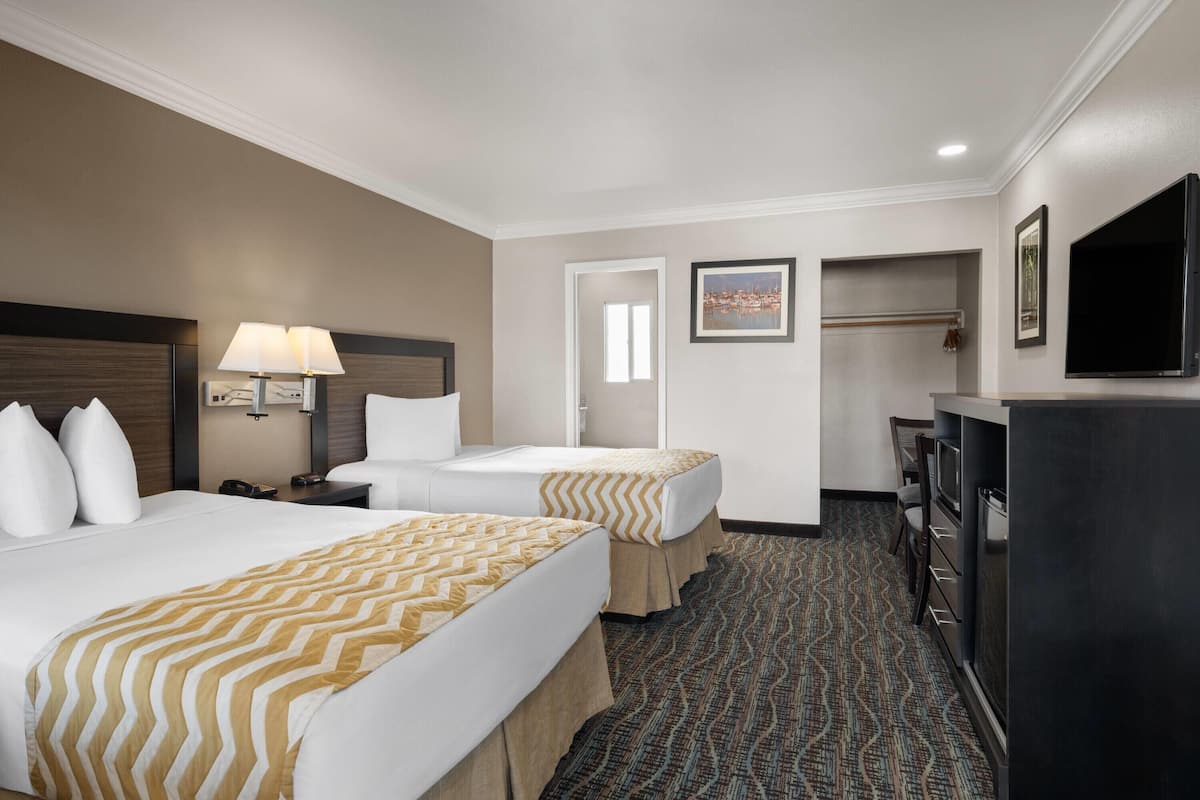 A hotel room with two beds, a desk, a television, and a wardrobe.