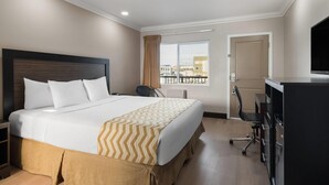 Une chambre d’hôtel équipée d’un lit, d’un bureau, d’une chaise, d’une télévision et d’une fenêtre donnant sur un paysage agréable.