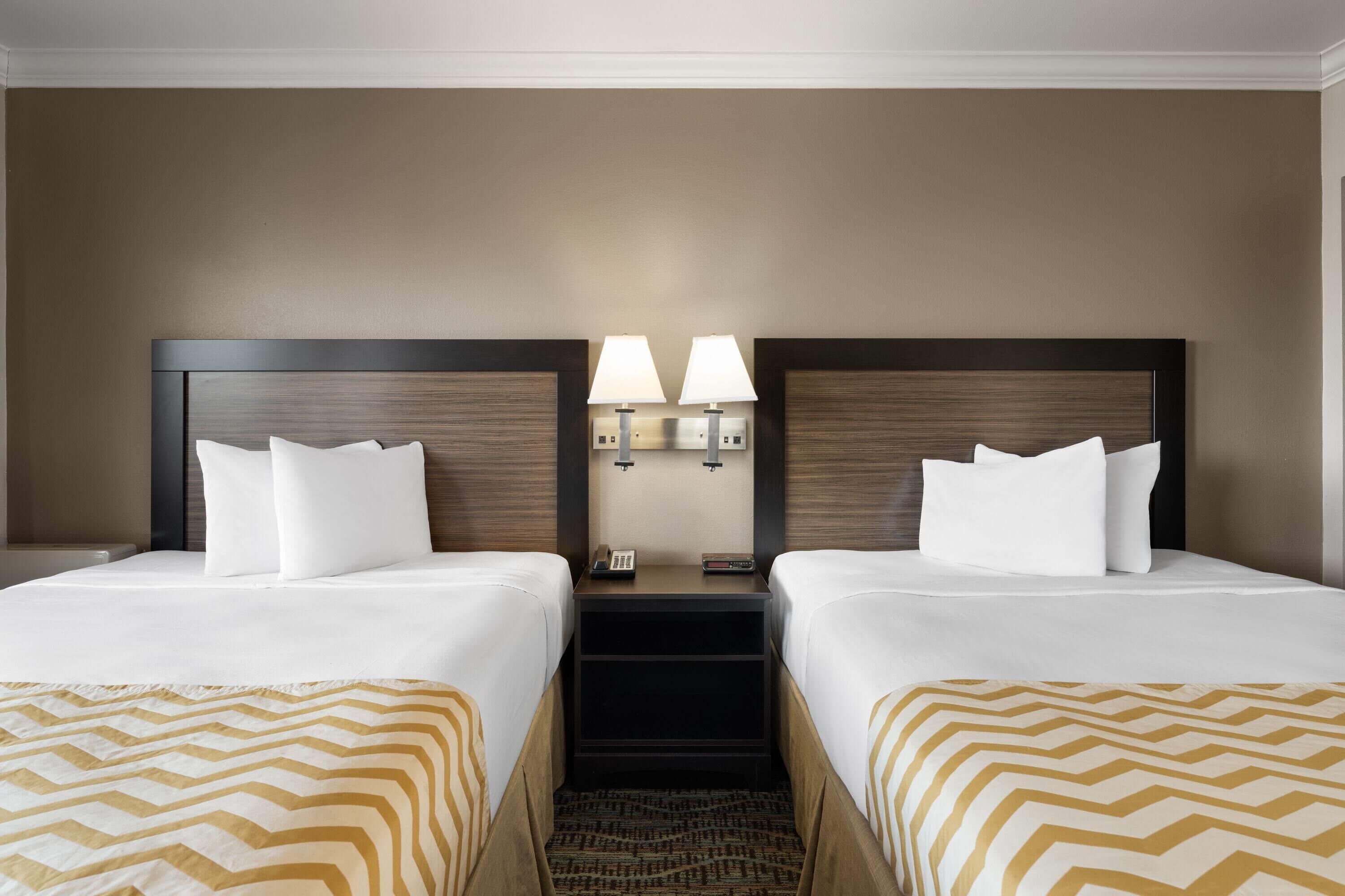 A hotel room with two beds, a nightstand with lamps, and a telephone.