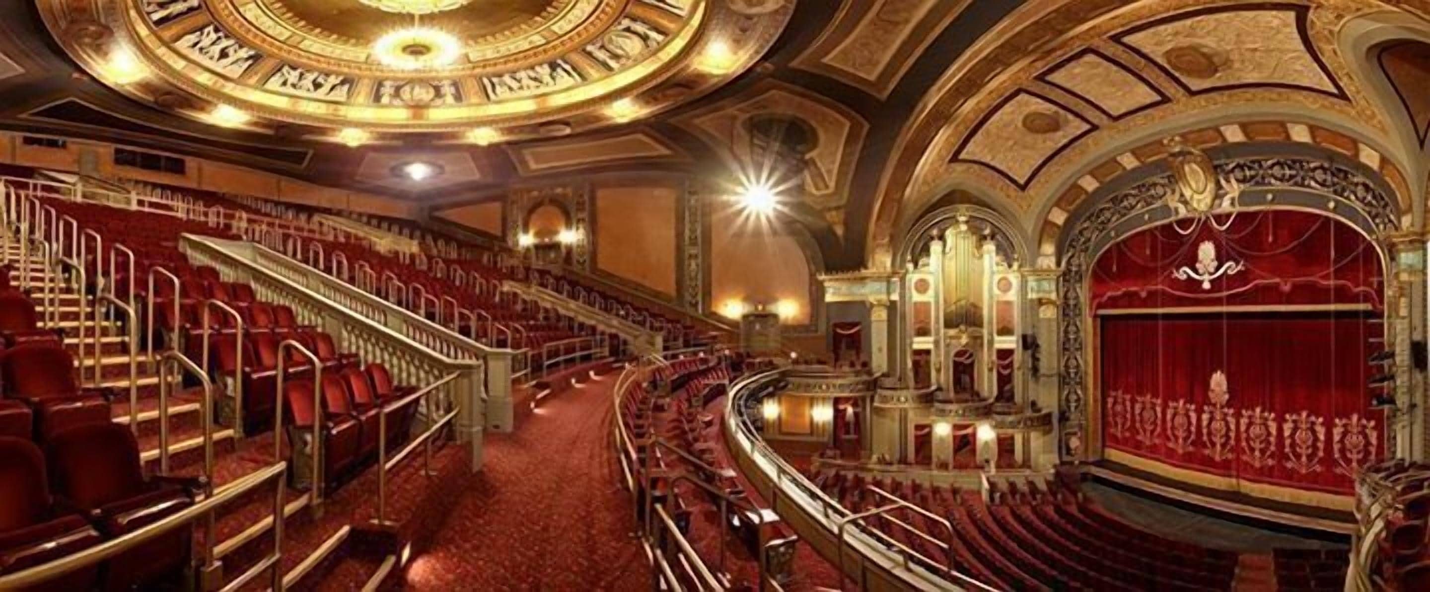 Un teatro con varios niveles de asientos, detalles arquitectónicos ornamentales y una gran zona de escenario.