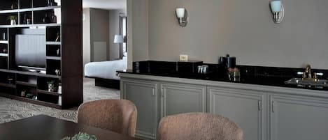 A modern hotel room with a dining area, a kitchen, and a living area.