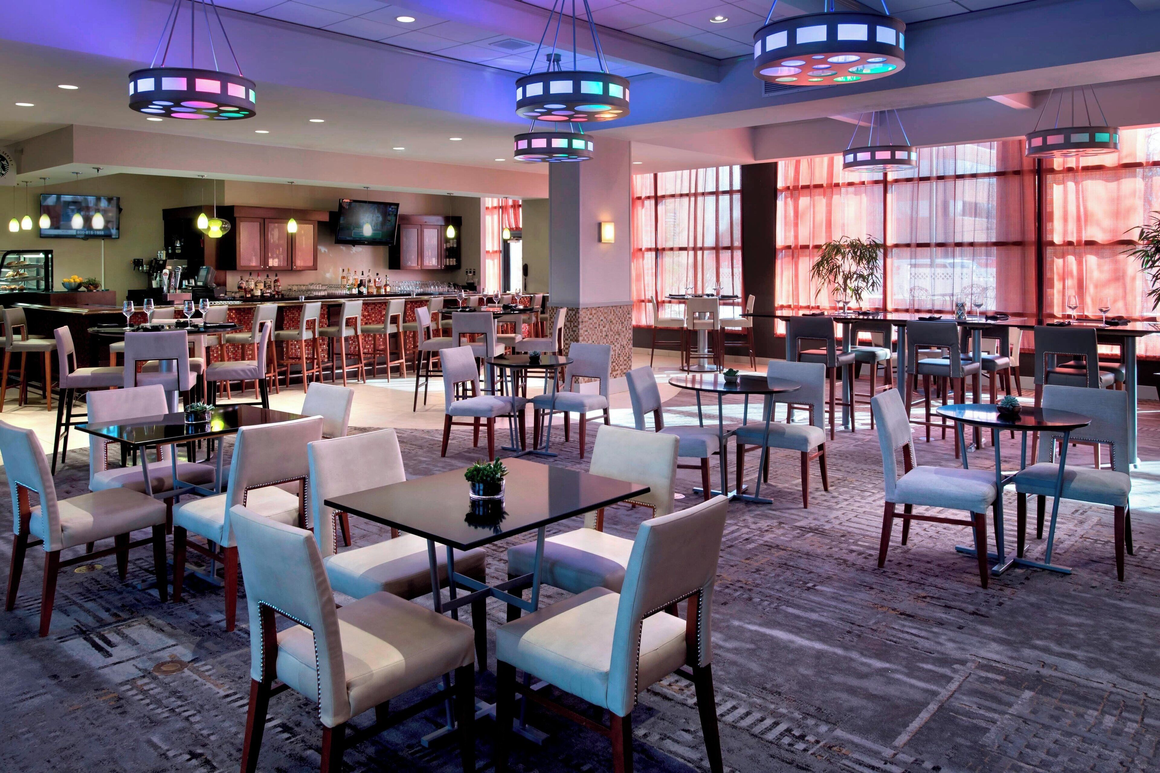 A hotel lobby with multiple seating areas, a bar, and a television screen.