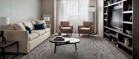 A modern living room with a sofa, two armchairs, a coffee table, and a bookshelf.