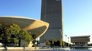 A modern architectural complex with a prominent curved building and a tall skyscraper in the background.