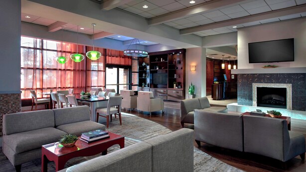 A spacious living area with a large sofa set, a dining table with chairs, and a fireplace. - Marriott Albany (Albany)
