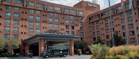 Un hotel Marriott con fachada de ladrillo, entrada cubierta y área de estacionamiento con una camioneta.