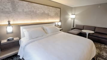 Una habitación de hotel con una cama grande, un sofá, una mesita y un mapa mural.