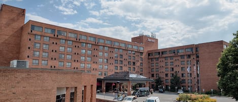 Un hotel de ladrillo grande con varios pisos, un letrero de Marriott y un estacionamiento con varios autos.