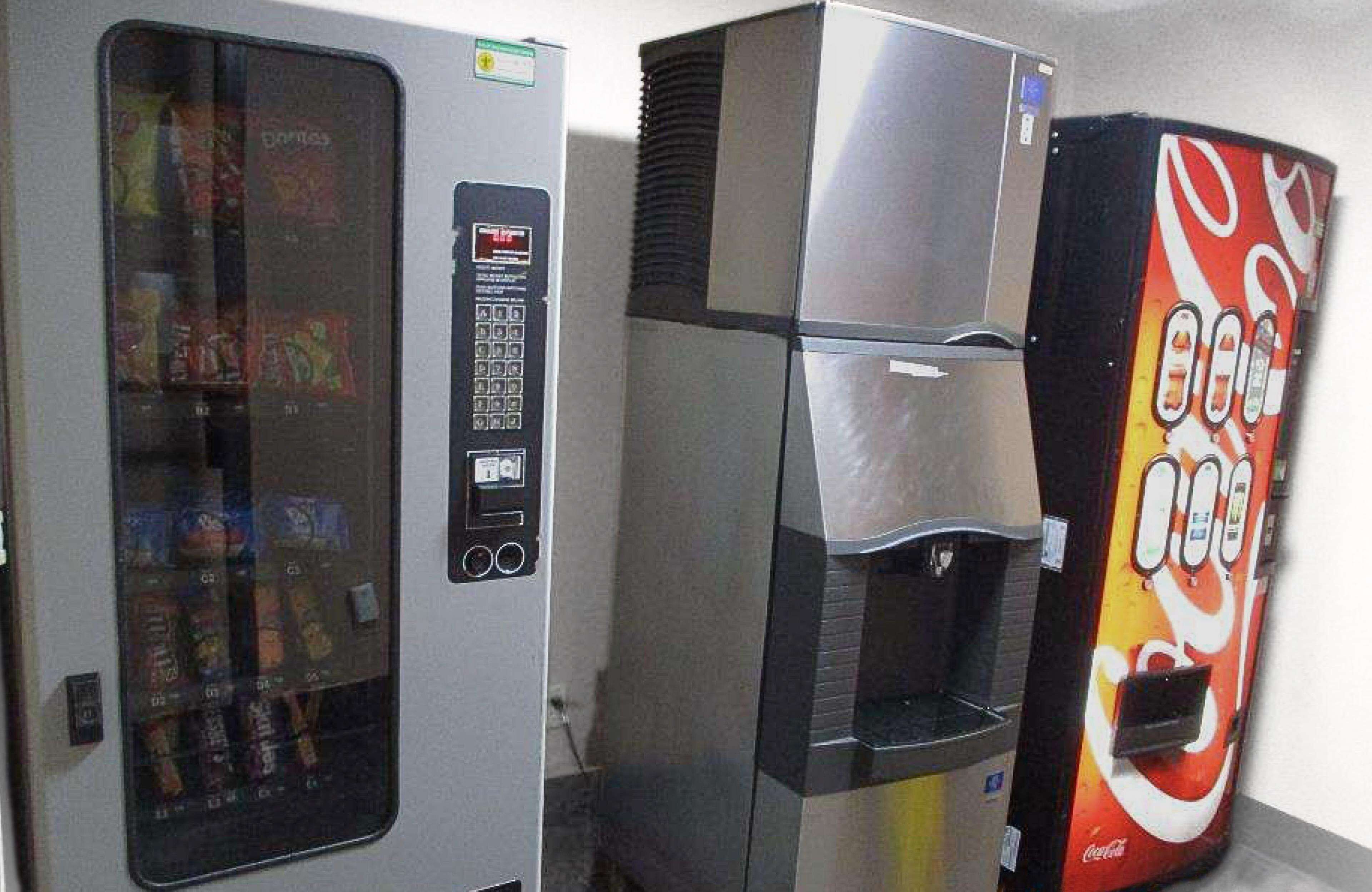 Ein Getränkeautomat mit Coca-Cola-Logo und einer Aufgussvorrichtung.