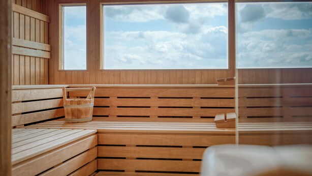 A wooden sauna with benches and a window. - Parkhotel Hameln (Hamelin)