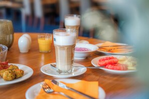A breakfast table with plates of food, a glass of milk, and a glass of orange juice. - Parkhotel Hameln (Hamelin)