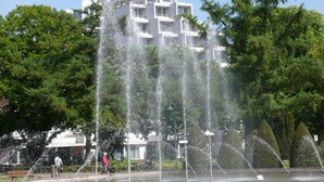 A hotel with a fountain in the foreground and a building with a sign reading "PARKHOTEL" in the background. - Parkhotel Hameln (Hamelin)