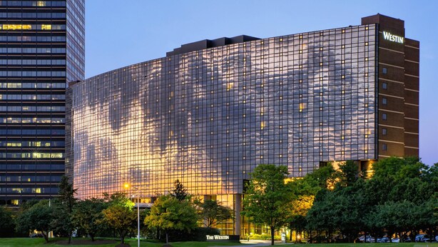 A modern hotel with a reflective glass facade, a prominent "WESTIN" sign, and a landscaped front yard with trees. - The Westin Southfield Detroit (Southfield)