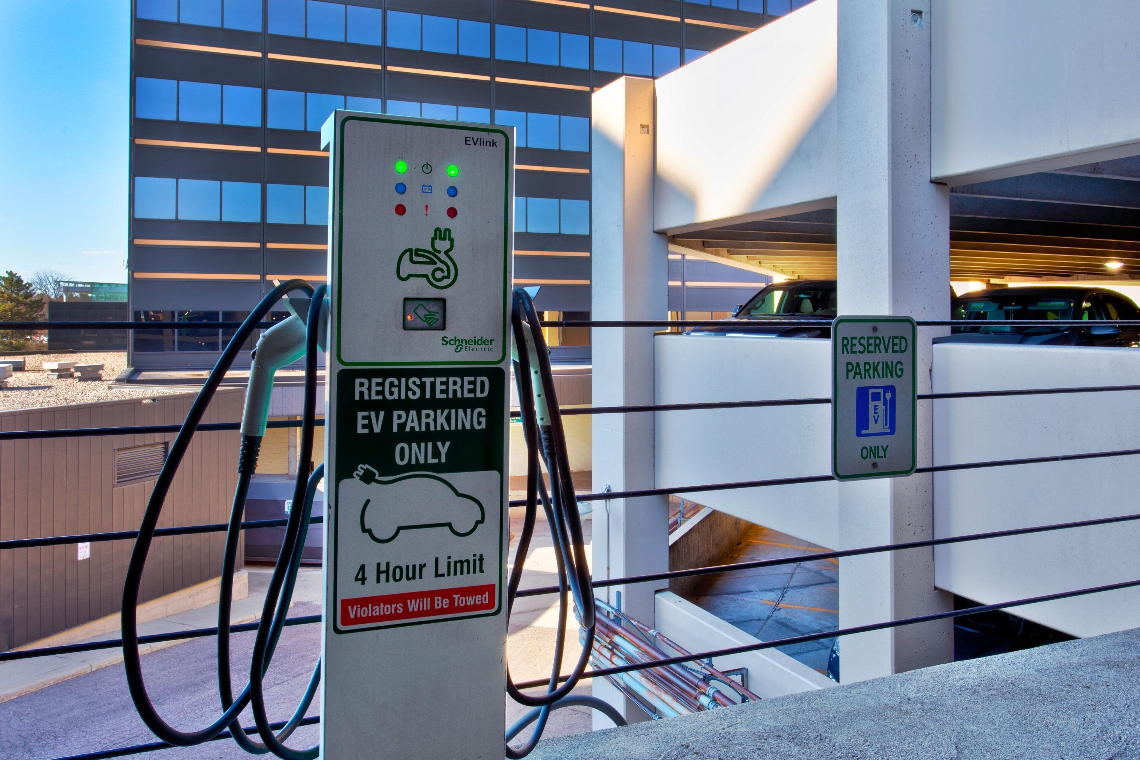 Una estación de carga para vehículos eléctricos con un cartel de límite de estacionamiento de 4 horas.