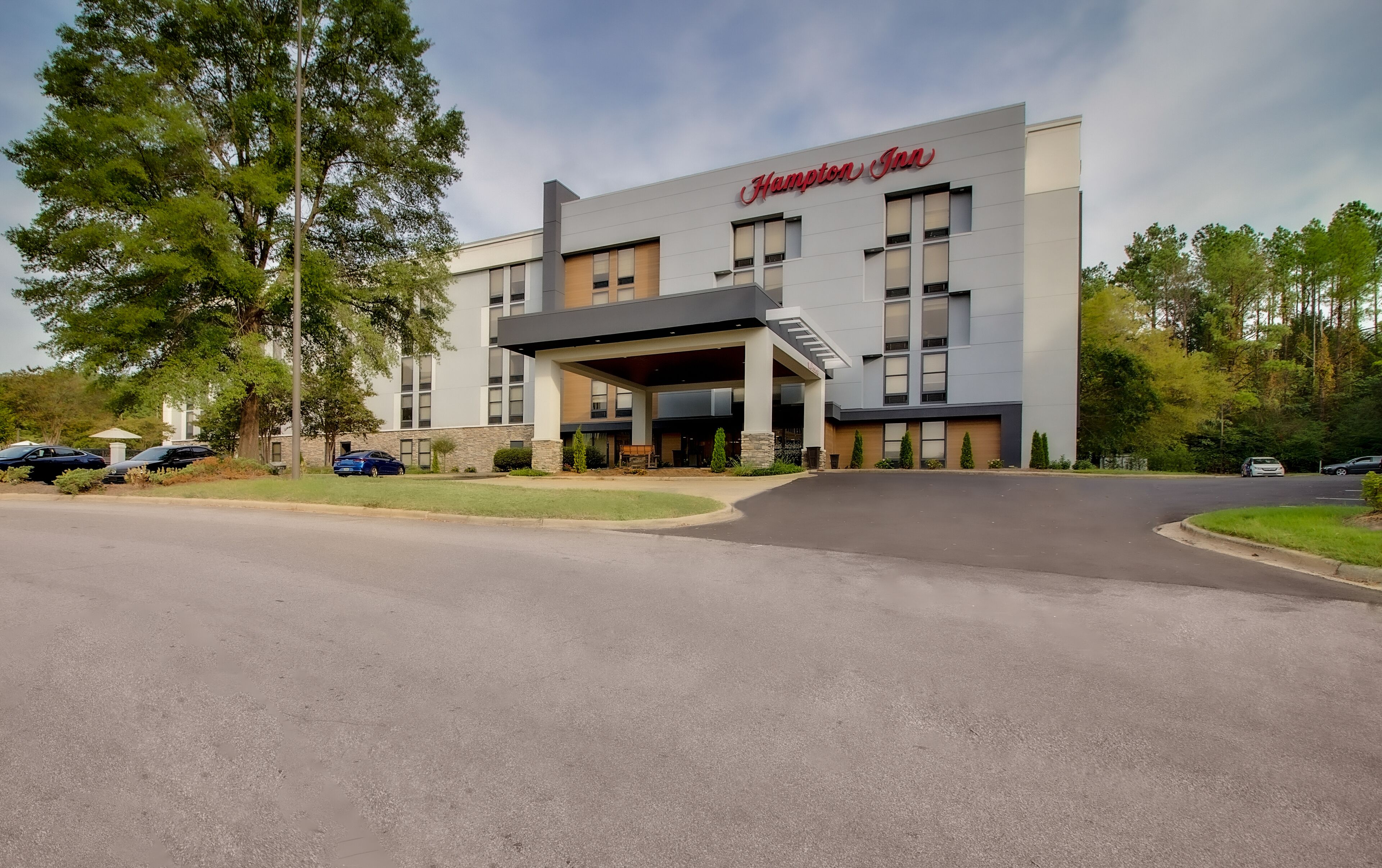 Ein Hampton Inn mit modernem Design, inklusive überdachter Zufahrt und Parkplatz.