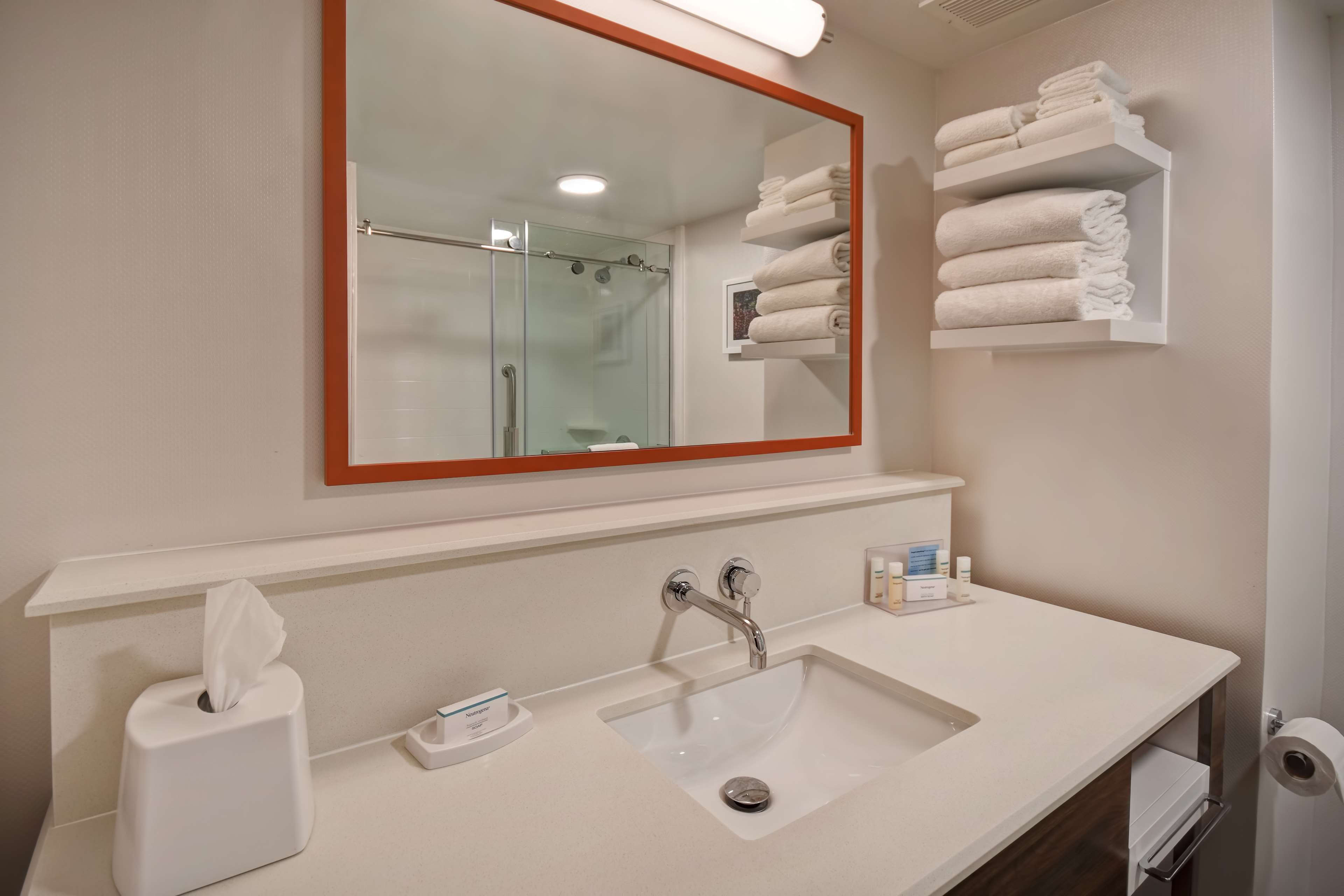 A bathroom with a large mirror, a sink, a towel rack, and a toilet.