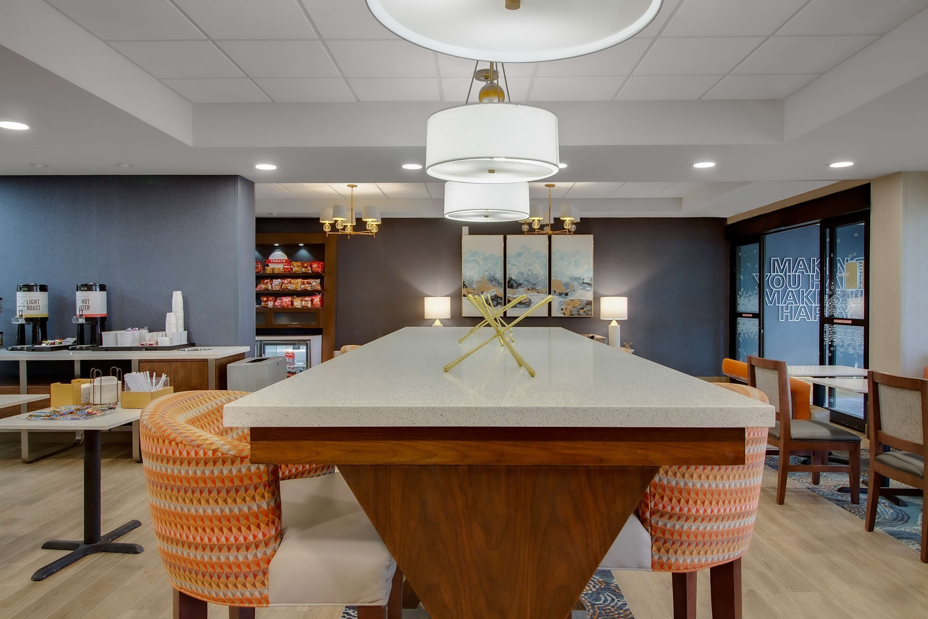 A modern dining area with a central island, seating, and a view of the kitchen.