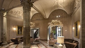 Un vestíbulo amplio con techos altos, columnas ornamentales y una variedad de zonas de estar, incluyendo sofás y sillones.