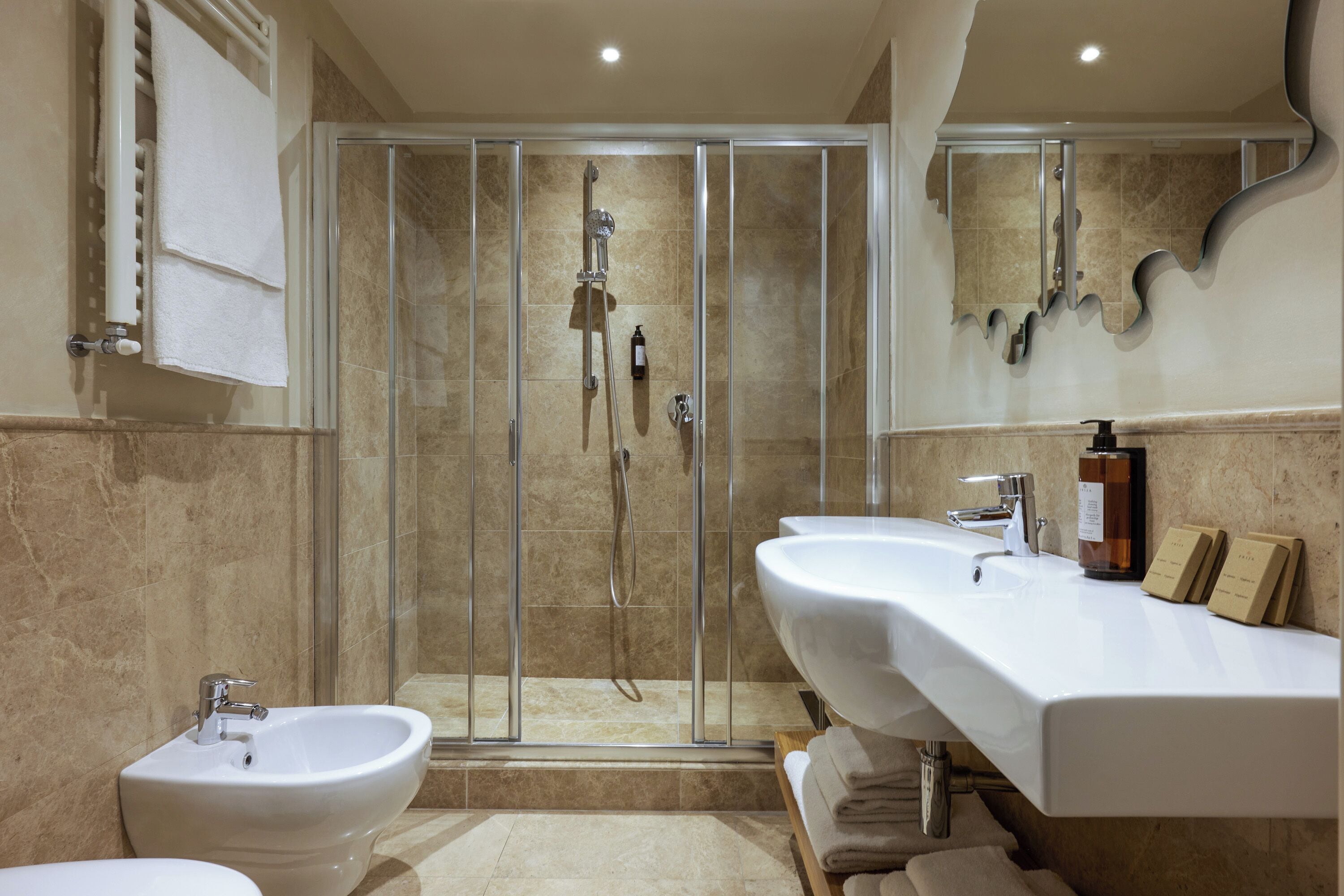 Un baño moderno con ducha de vidrio, dos lavamanos y un bidé.