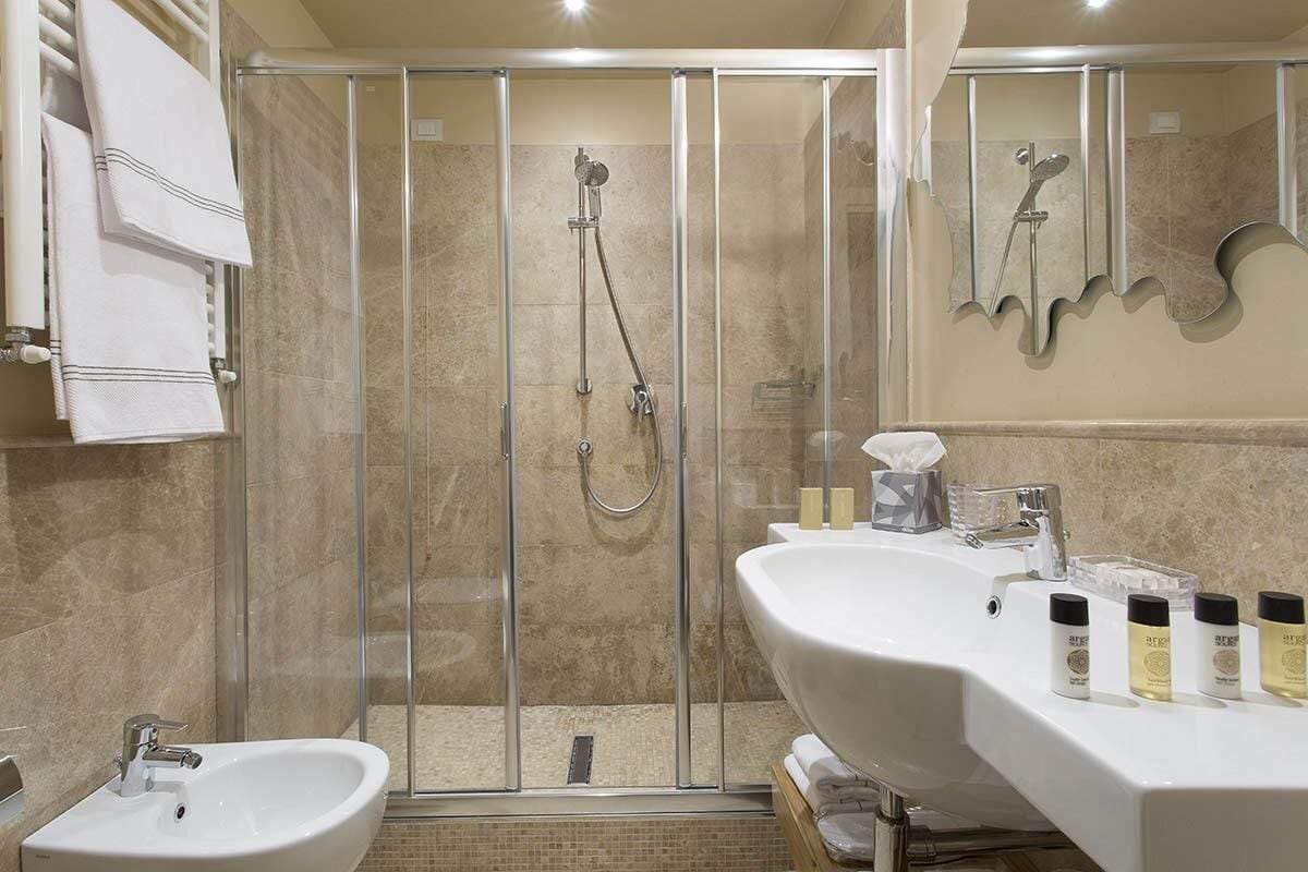 A modern bathroom with a glass-enclosed shower, a double sink vanity, and a mirror with a unique wavy design.