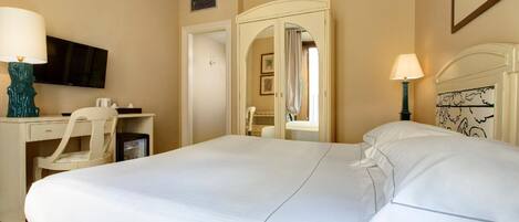 Una habitación de hotel con cama, escritorio, silla, televisor, espejo y lámpara.