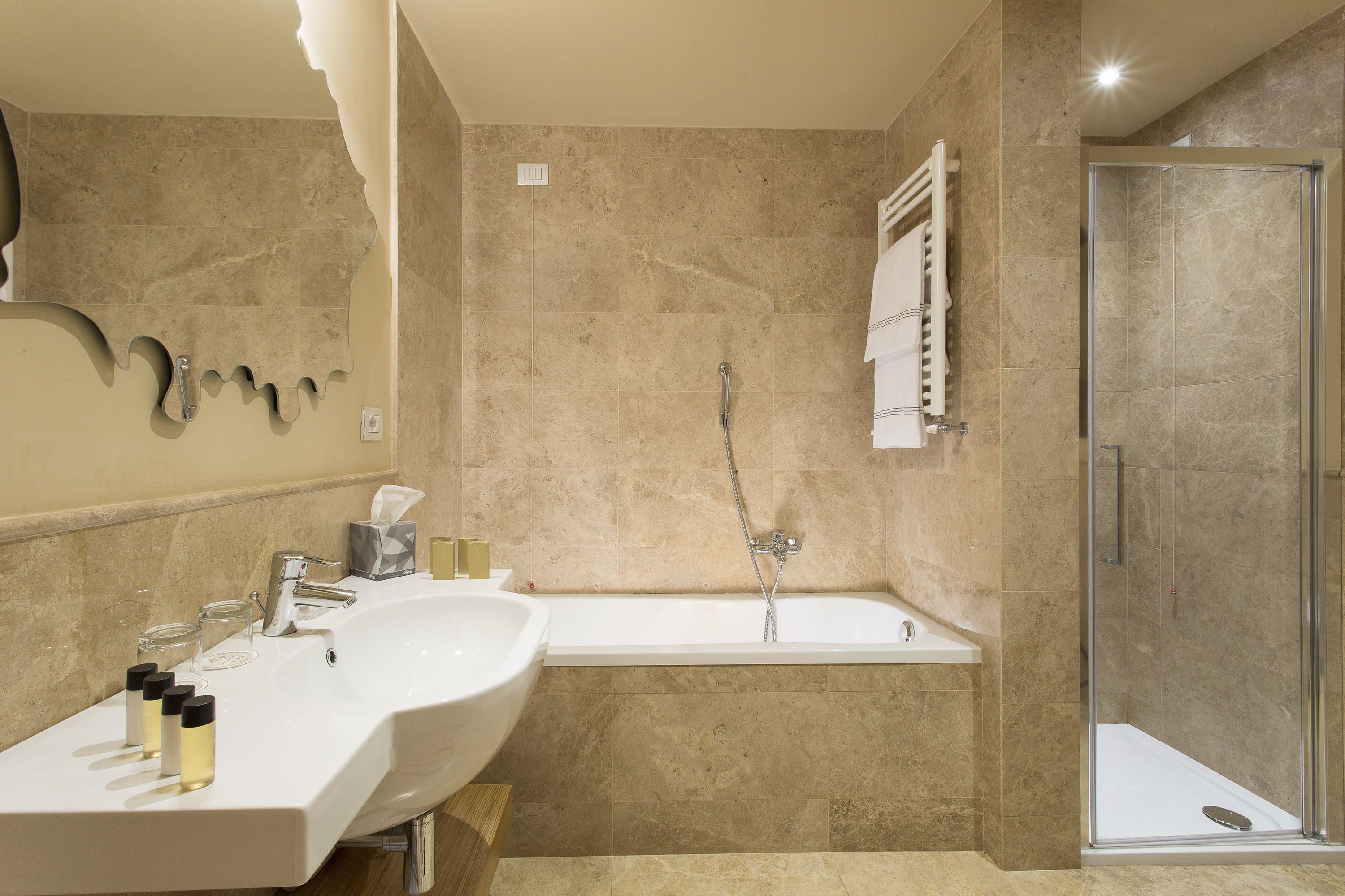 A modern bathroom with a double sink, a bathtub, and a glass-enclosed shower.