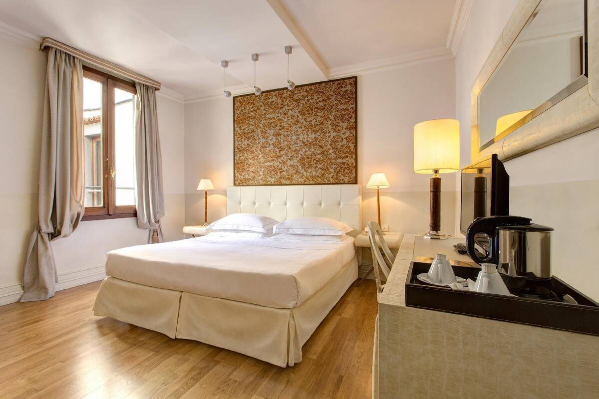 Une chambre d’hôtel avec un grand lit, deux lampes de chevet, une machine à café et un miroir au mur.