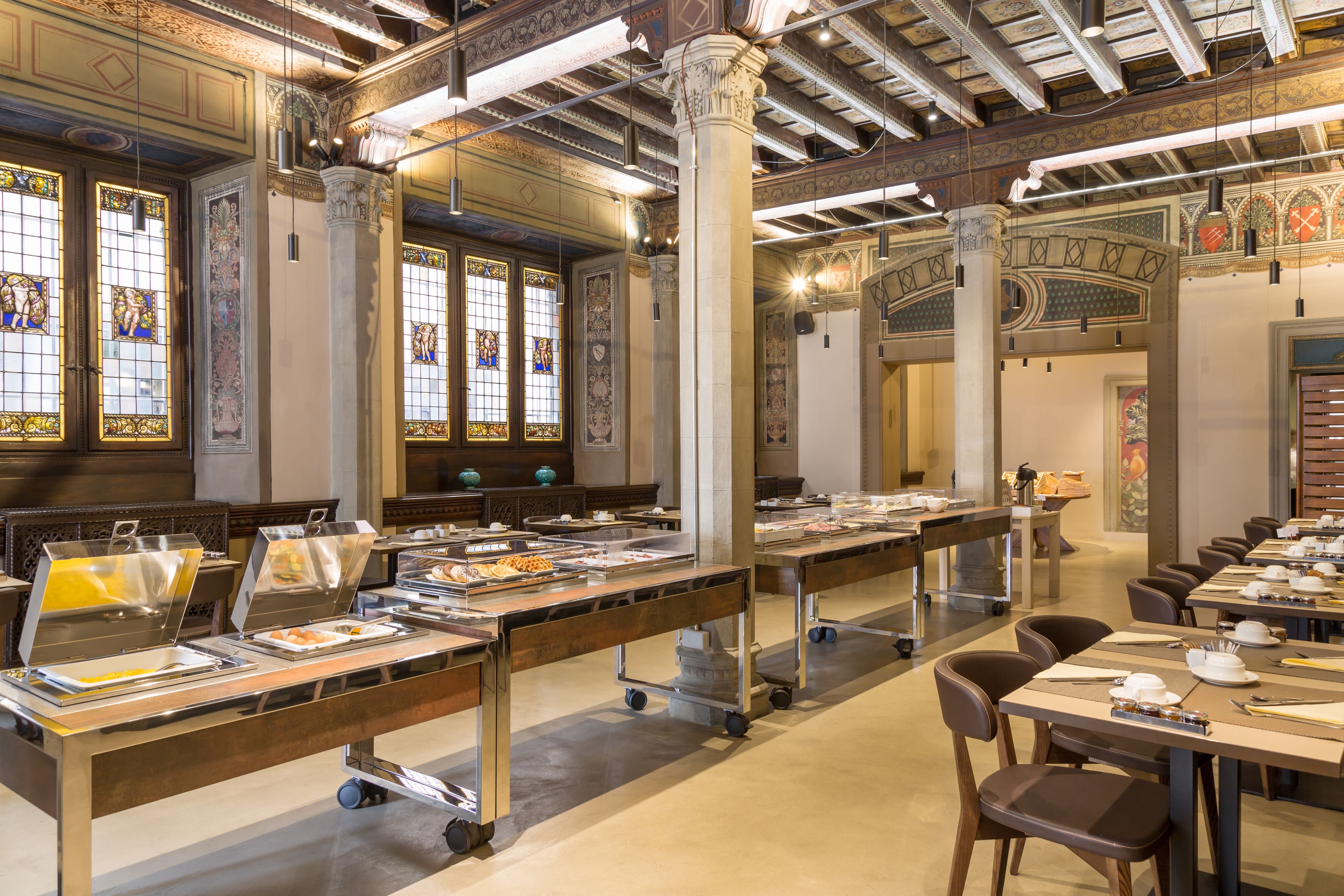 Een eetgedeelte met buffetbediening, met een lange tafel met verschillende food stations en stoelen.