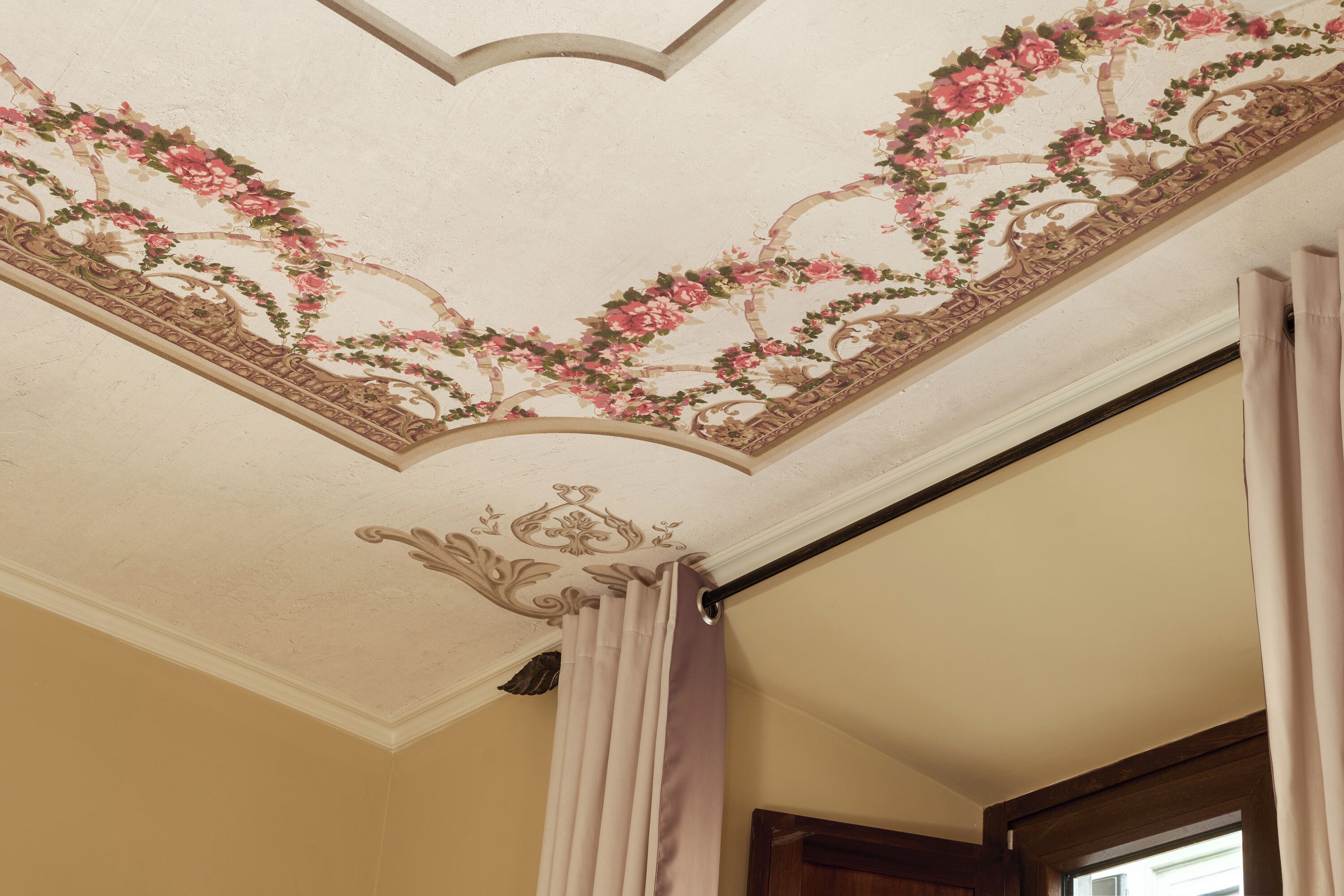 Techo con diseños florales y ornamentales, una puerta con cortina y un marco de madera.