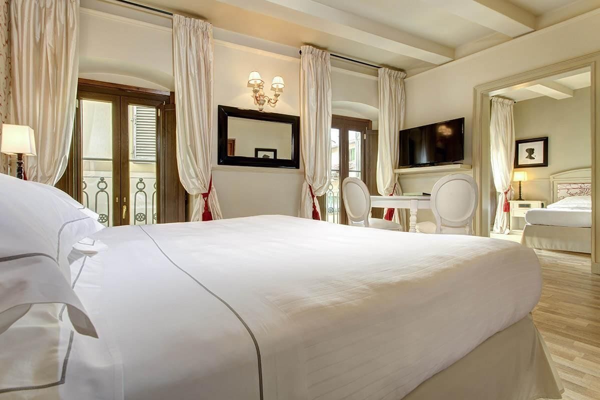 Une chambre d’hôtel avec un grand lit, un bureau avec une chaise, une télévision et une salle de bain équipée d’un miroir et de toilettes.