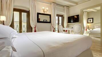 Een hotelkamer met een groot bed, een bureau met stoel, een televisie en een badkamer met spiegel en toilet.