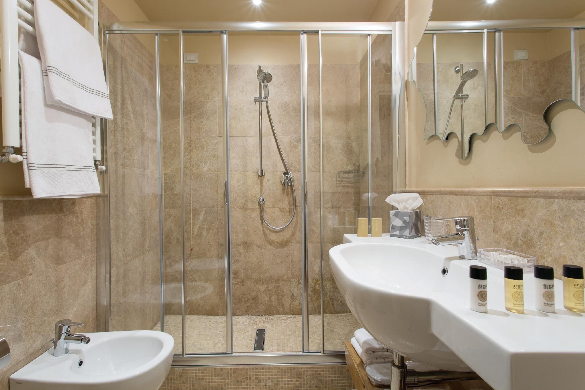A modern bathroom with a glass-enclosed shower, a sink, and a vanity with toiletries.