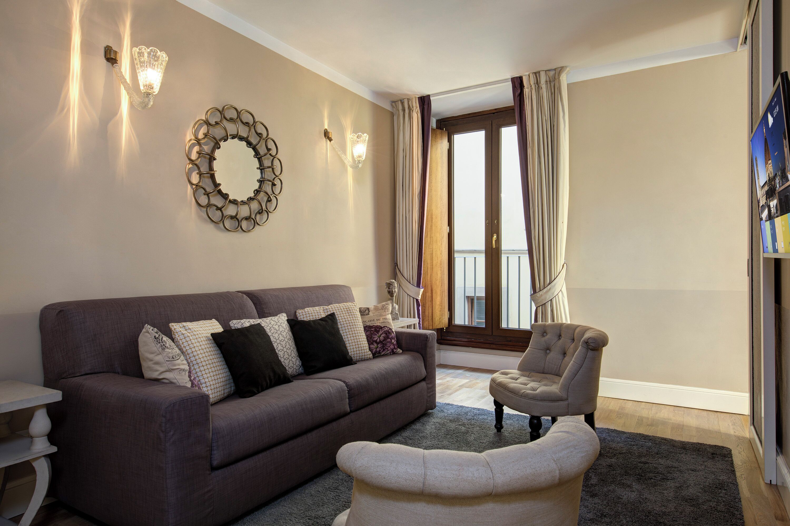 Un salon avec un canapé, un fauteuil et un miroir décoratif au mur.