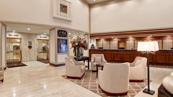 A spacious lobby with a marble floor, a reception desk, and seating areas.
