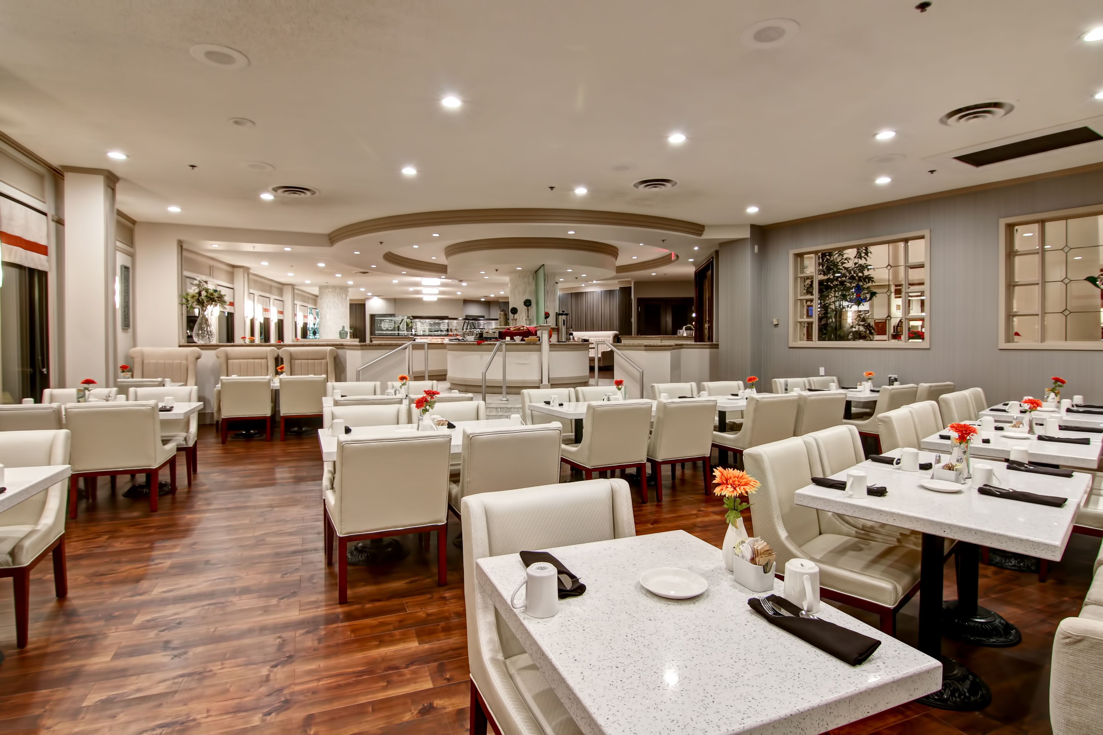 Un ristorante spazioso con numerosi tavoli e sedie, un pavimento in legno lucido e un moderno design del soffitto.
