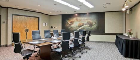 Une salle de conférence équipée d’une longue table, de nombreuses chaises et d’un grand écran.