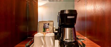 Een hotelkamer met een koffiezetapparaat op een dienblad, een glazen scheidingswand en een houten wand.
