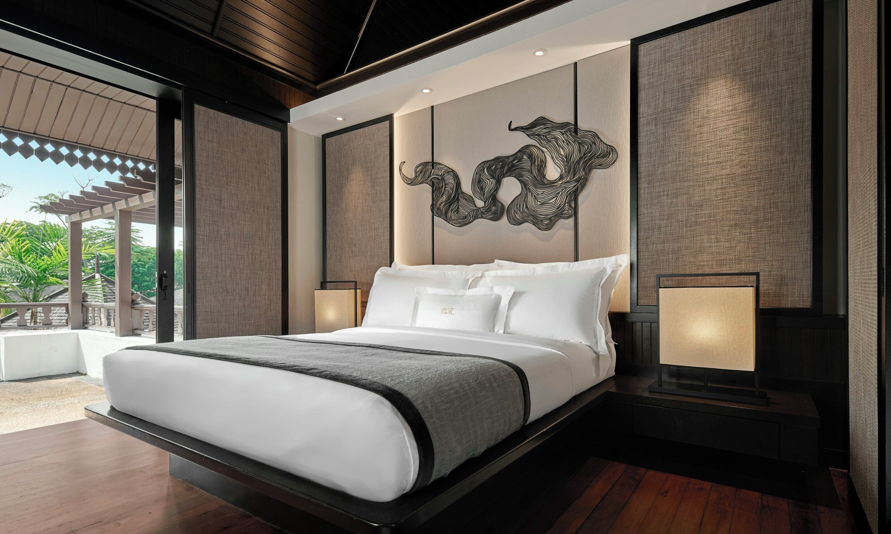 A modern bedroom with a large bed, two bedside tables, and a decorative wall piece.
