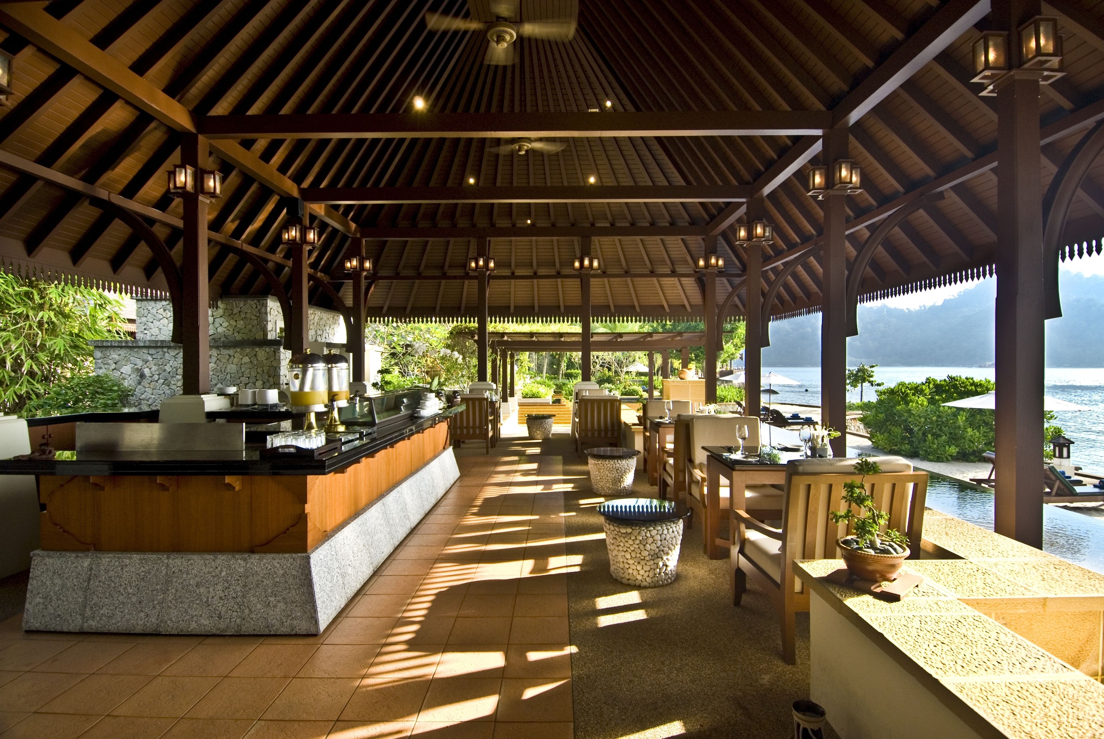 Un espacio al aire libre techado con un bar, asientos y vista al mar.