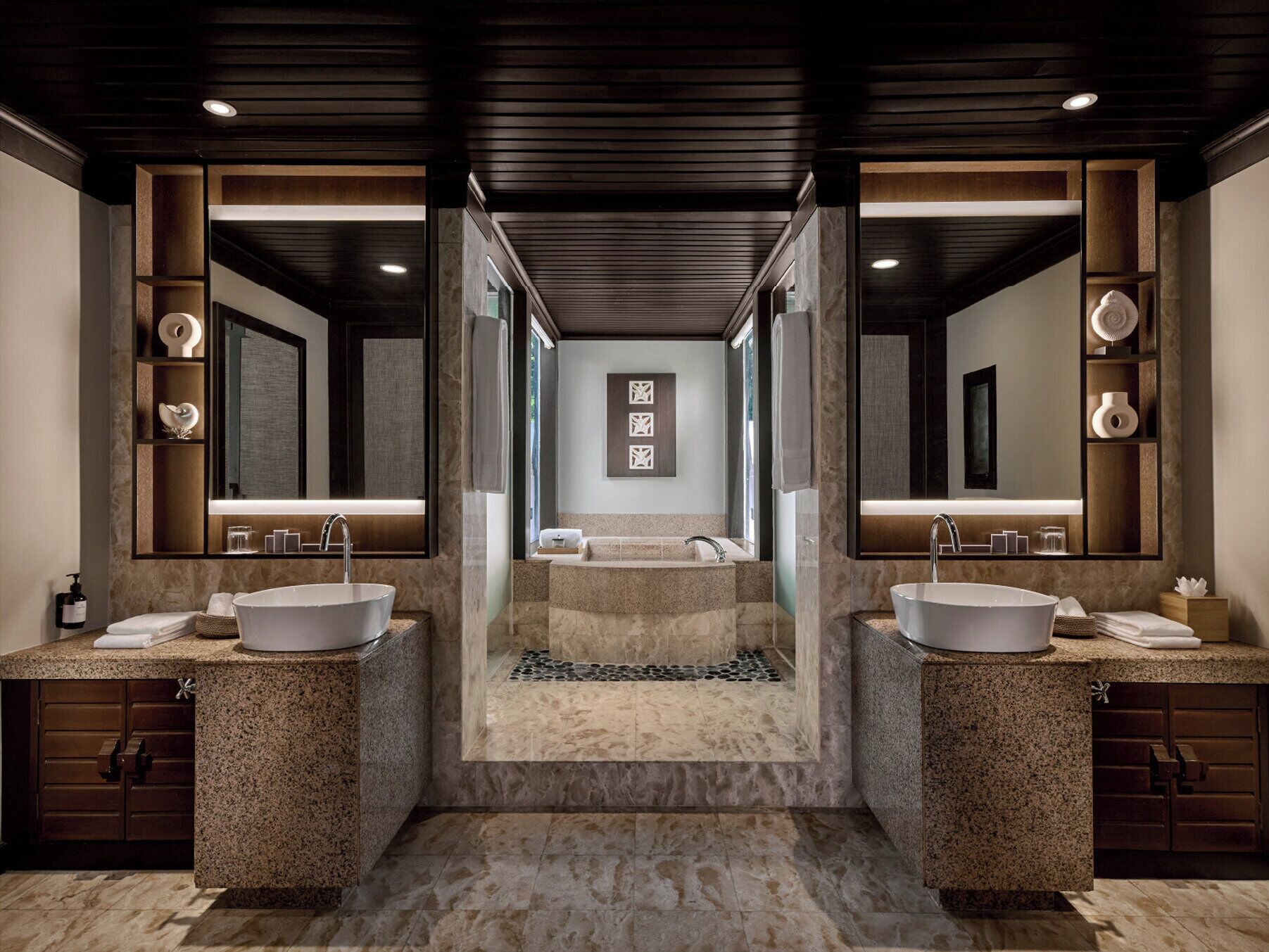 A modern bathroom with two sinks, a large mirror, and a central staircase leading to a shower area.