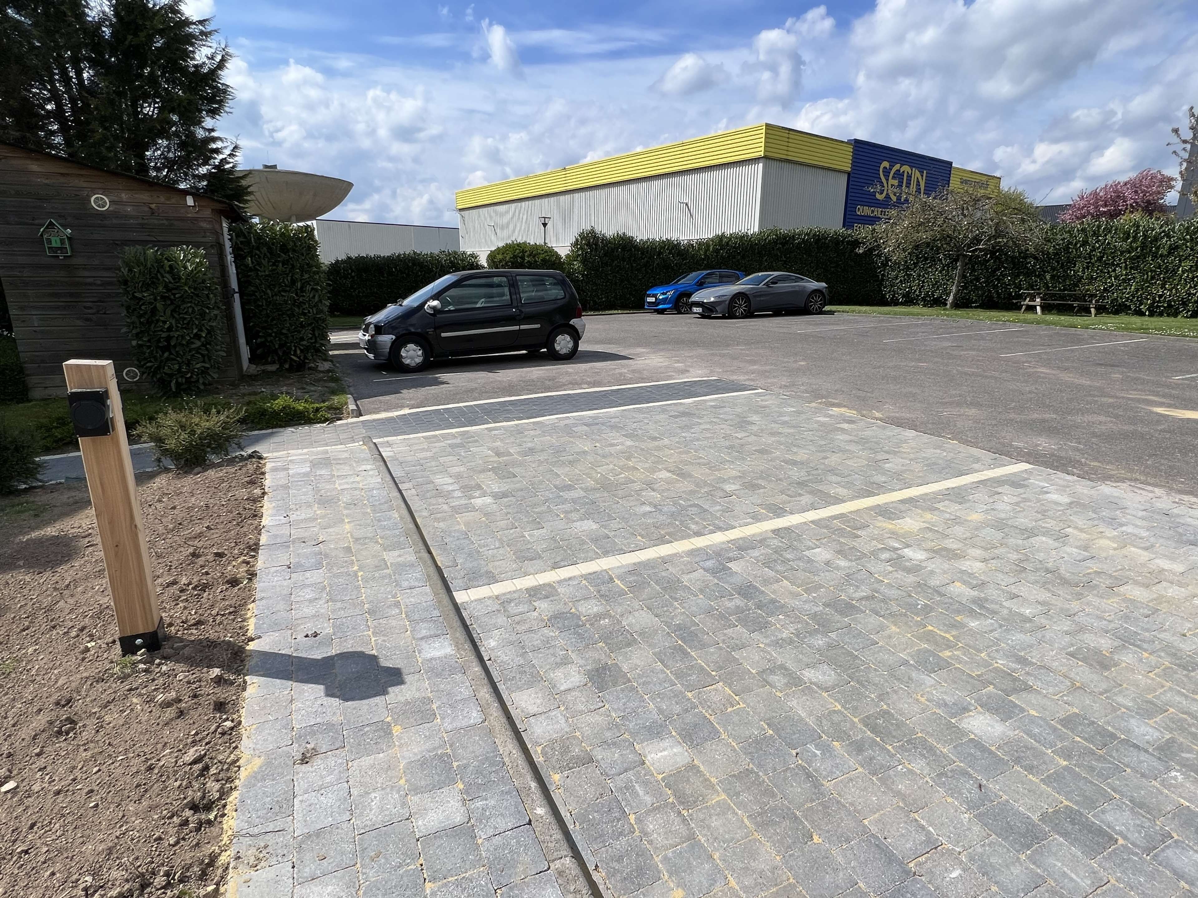Un área de estacionamiento con un sendero pavimentado que lleva a un edificio con techo amarillo.