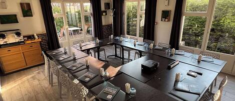 Un salón de conferencias con una larga mesa, sillas y vistas al exterior a través de amplios ventanales.