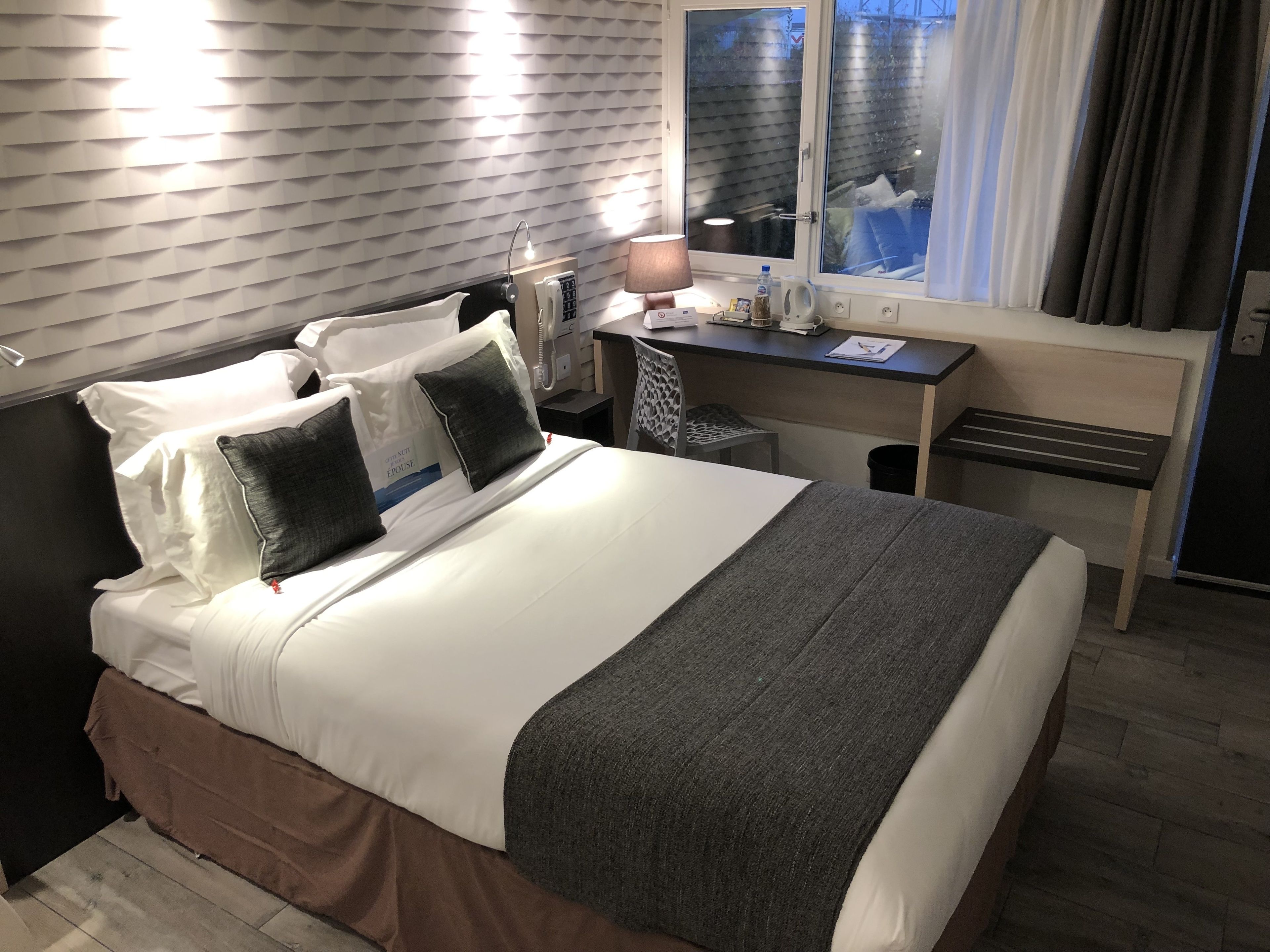 Een hotelkamer met een groot bed, een bureau en een raam met gordijnen.